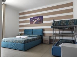 a bedroom with a blue bed and a striped wall at Hotel Rodi Beach FRONTE SPIAGGIA in Rodi Garganico +14 photos