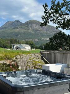 a hot tub with water in it with mountains in the background at Architectural gem with fjord view in Holmedal