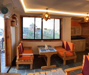 a living room with a table and chairs and windows at Bandipur Samira Hotel & Homestay - your comfort in heart of Bandipur in Bandipur
