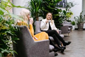 two women sitting in chairs in a room with plants at Hestia Hotel Ilmarine in Tallinn