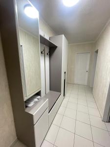 a bathroom with a white tiled floor and white cabinets at RentHouse Samal in Astana +2 photos