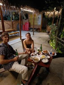 a man and woman sitting at a table with food at Danh Lam Homestay in Kon Rung (1)
