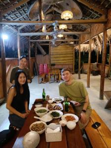 a group of people sitting around a wooden table with food at Danh Lam Homestay in Kon Rung (1)