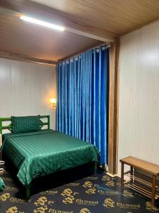 a bedroom with a green bed and blue curtains at Danh Lam Homestay in Kon Rung (1)