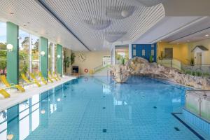 a large swimming pool with yellow chairs in a hotel at IFA Graal-Müritz Hotel & Spa in Graal-Müritz