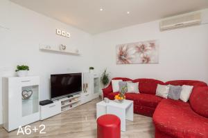 a living room with a red couch and a tv at Apartmani Dalibor, Stanići - Omiš in Stanići