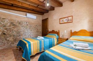 a bedroom with two beds and a stone wall at YourHouse Padri de Inca in Inca +29 photos