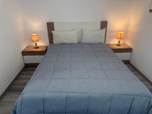 a bedroom with a blue bed with two lamps at Seaview Suite in Caniço