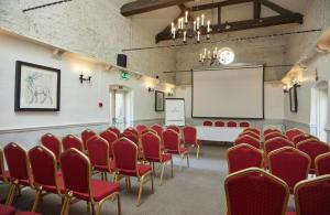 a conference room with red chairs and a white screen at Fieldhead Hotel by Greene King Inns in Markfield