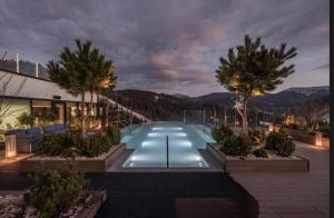 a pool at night with palm trees and a building at PANORAMA Chalet MOUNTAIN RESIDENCE in Bukovel