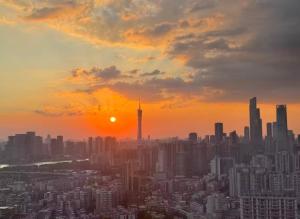 a city skyline at sunset with the sun setting at Soluxe Hotel Guangzhou in Guangzhou