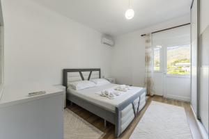 a white bedroom with a bed and a window at Castle Serenity Home 3BR with Free Parking by PikHost in Gjirokastër