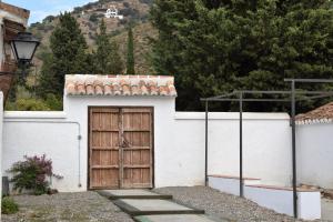 een klein wit gebouw met een houten deur bij Cortijo Don Rodrigo in El Chorro