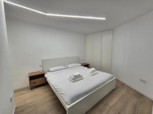 a white bedroom with a bed and a wooden floor at Vibre Canaris - Las Americas in Playa de las Americas