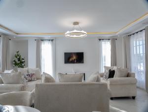 a white living room with couches and a chandelier at Ngao #220 Swara Ranch in Nanyuki