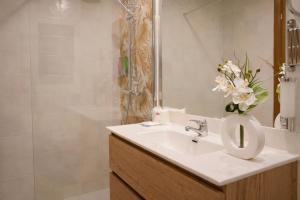 a bathroom with a sink and a vase of flowers at Aston Hotel in Andorra la Vella +39 photos
