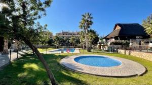 a swimming pool in a park with trees and a building at Sonne - Golf - 4Pers - Komfort - Apartments in Fuente-Álamo de Murcia