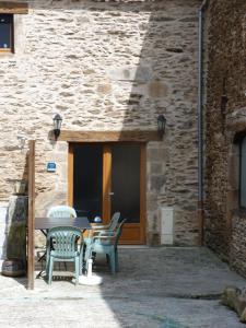 a table and chairs in front of a stone building at Oustalou in Belcastel +3 photos