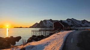 a house on the shore of a lake with the sunset at Solodden, Authentic rorbu in Lofoten in Sennesvik