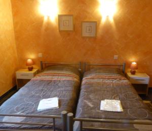 two beds in a room with two lamps on the wall at Oustalou in Belcastel