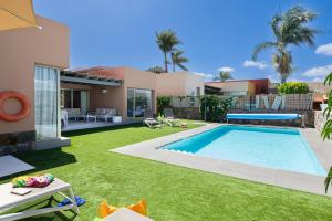 a backyard with a swimming pool and a house at Yellow Sunshine 8 by VillaGranCanaria in Salobre