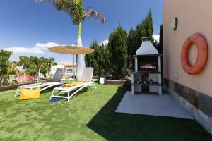 a backyard with a grill and chairs and an umbrella at Yellow Sunshine 8 by VillaGranCanaria in Salobre