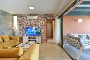 a living room with a couch and a tv at Yellow Sunshine 8 by VillaGranCanaria in Salobre +71 photos