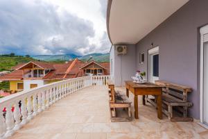 a balcony with a wooden table and a bench at Hometown Apartment by PikHost in Gjirokastër