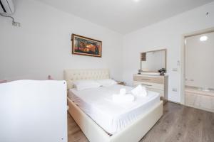 a white bedroom with a white bed and a mirror at Hometown Apartment by PikHost in Gjirokastër