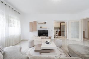 a white living room with a couch and a tv at Hometown Apartment by PikHost in Gjirokastër