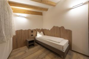 a small bedroom with a bed with a wooden headboard at Vacanze la Malga in Predazzo