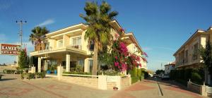 a house with a palm tree in front of a street at Kamer Exclusive Hotel & Suites in Çeşme