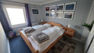 a bedroom with a bed with white sheets and pillows at Solodden, Authentic rorbu in Lofoten in Sennesvik
