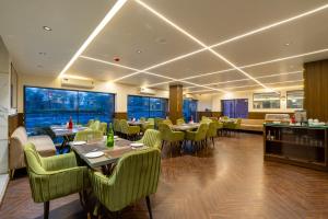 a restaurant with tables and green chairs and windows at Arch The Venus - Free Airport Pickup or Drop in New Delhi