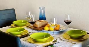 a table with green bowls and plates and wine glasses at La Terrazza In Centro Dorgali in Dorgali