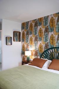 a bedroom with a green bed with a floral wallpaper at Jungle Room - Studio avec spa privé in Quéven