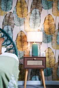 a lamp on a table next to a wall with leaves at Jungle Room - Studio avec spa privé in Quéven +12 photos