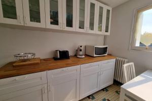 a kitchen with white cabinets and a microwave at Large family house 300m from the beach in Arcachon +18 photos