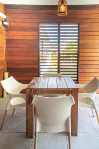 a dining room with a wooden table and white chairs at Bungalow Kaz Mendé in Sainte-Anne
