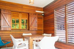 a dining room with a table and white chairs at Bungalow Kaz Mendé in Sainte-Anne