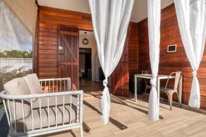 a living room with white curtains and a table and chairs at Bungalow Kaz Orchidée Oncidium in Sainte-Anne