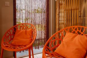 two orange chairs sitting in front of a window at Bungalow Kaz Orchidée Oncidium in Sainte-Anne