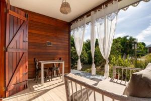 a balcony with a table and curtains on it at Bungalow Kaz Orchidée Oncidium in Sainte-Anne