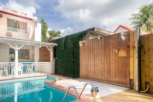 a pool with a wooden fence next to a house at Villa Kaz a Ramon in Port-Louis