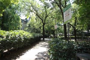 a sign in a park with bushes and trees at Guest House Dell'Affresco in Reggio Emilia