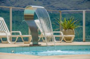 a water fountain in a swimming pool with chairs at Serra Palace Hotel in Ouro Branco