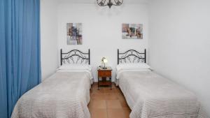 two beds in a room with blue curtains at El Olmo Posadas by Ruralidays in Posadas +24 photos