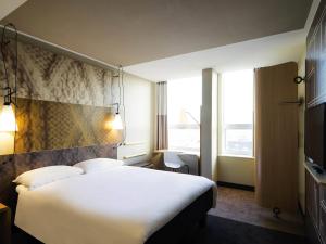 a hotel room with a white bed and a window at Ibis Den Haag City Center in The Hague