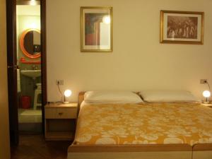 1 dormitorio con 1 cama, 2 lámparas y espejo en Albergo Corona, en Salsomaggiore Terme