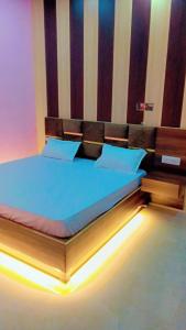a bedroom with a bed with blue sheets and a headboard at Pushpanjli grand inn in Ayodhya